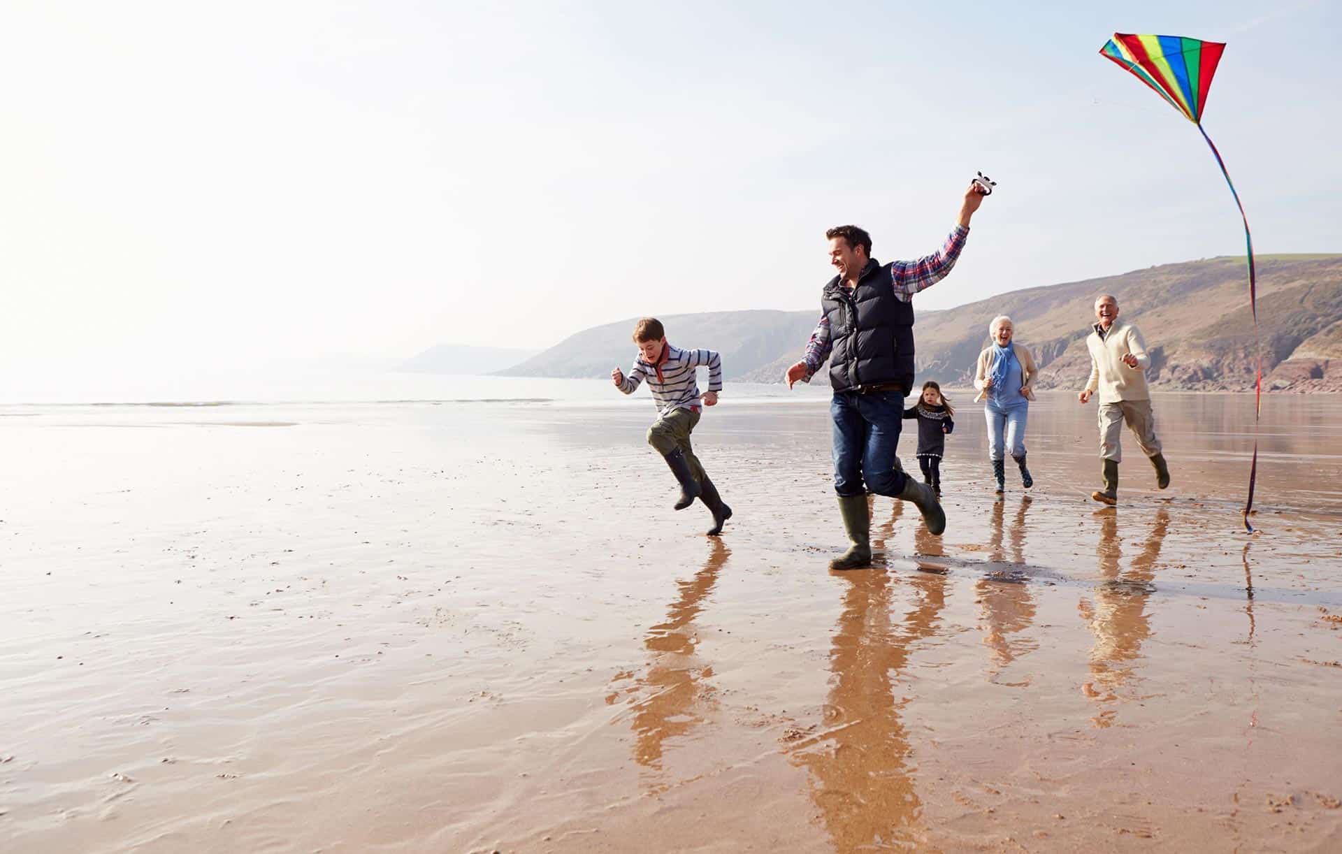 Family having fun running on the beach with a kite.